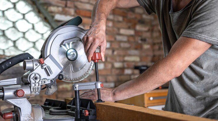 Foto gratuito un hombre con una tabla y una sierra de inglete de cerca, concepto de construcción y reparación.