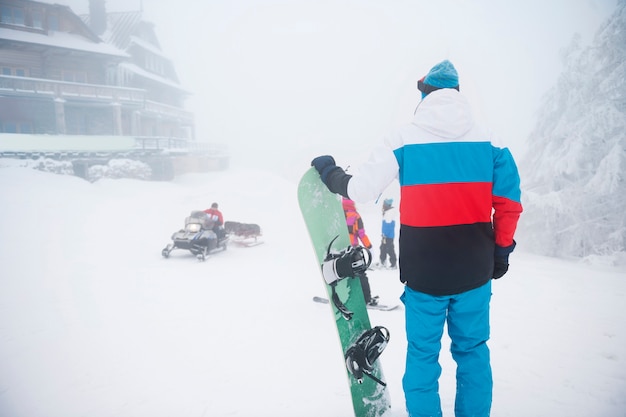 Hombre con tabla de snowboard durante el invierno