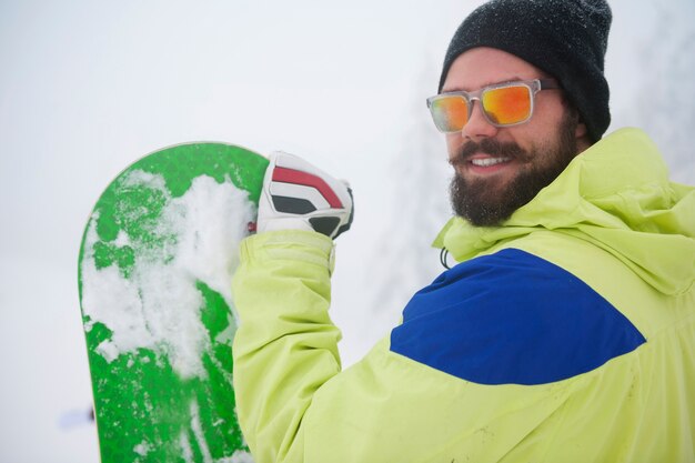 Hombre con tabla de snowboard durante el invierno