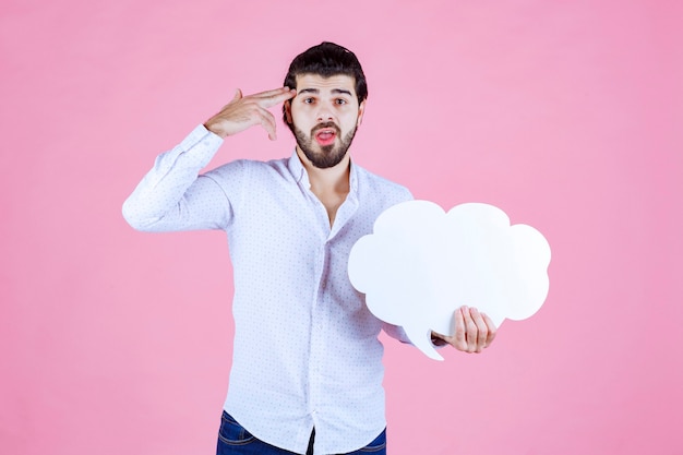 Foto gratuita el hombre con un tablero de ideas en forma de nube parece pensativo.