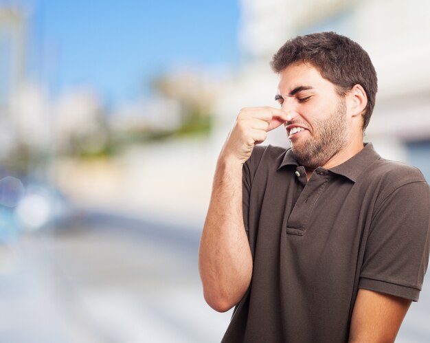 Hombre tapándose la nariz con cara de asco