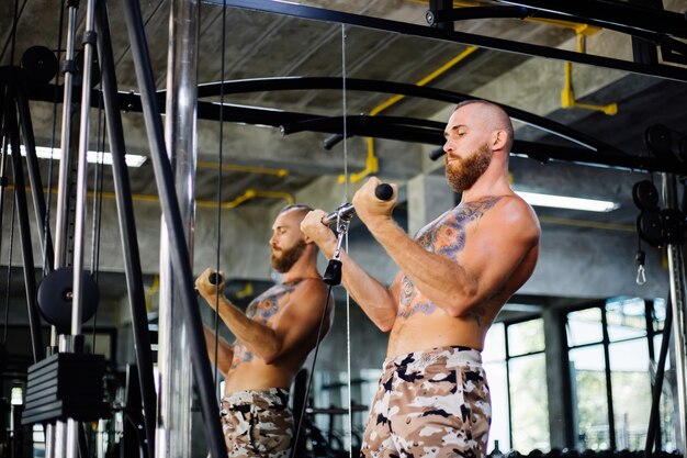 Hombre tatuado en forma haciendo ejercicio en el gimnasio