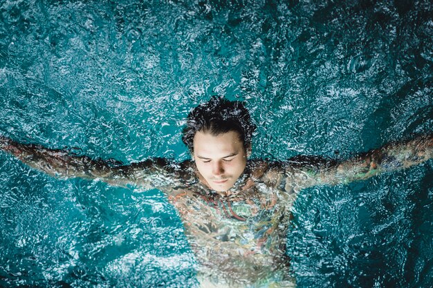 hombre tatuado en la piscina bajo la lluvia.