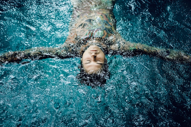 hombre tatuado en la piscina bajo la lluvia.