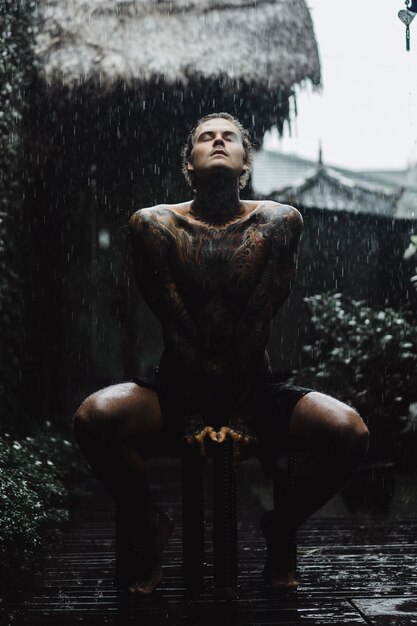 hombre tatuado posando bajo la lluvia