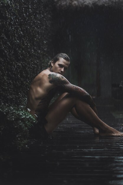 hombre tatuado posando bajo la lluvia