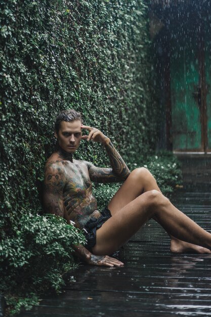 hombre tatuado posando bajo la lluvia
