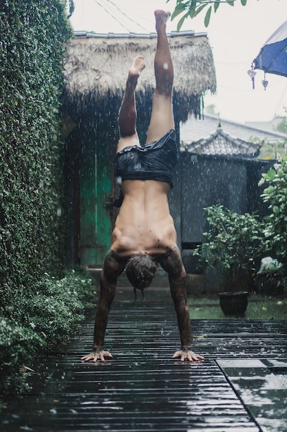 hombre tatuado posando bajo la lluvia