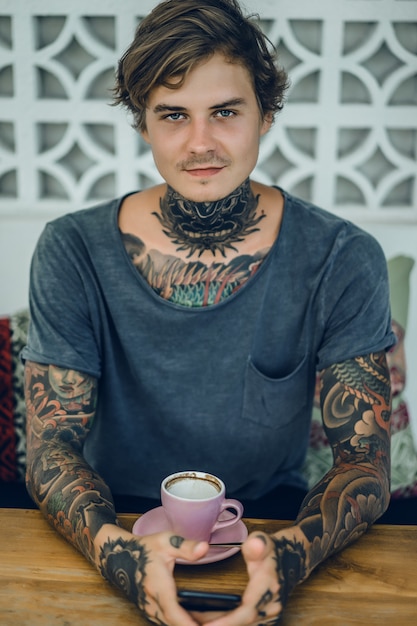 Foto gratuita hombre tatuado tomando café en una cafetería