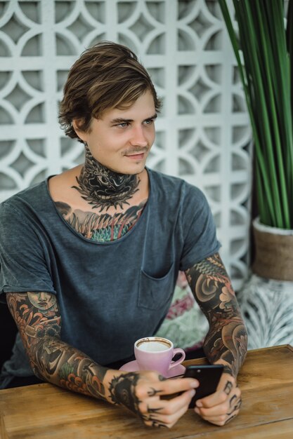 hombre tatuado tomando café en una cafetería