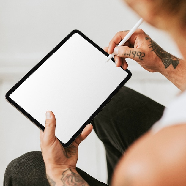 Hombre tatuado trabajando en maqueta de pantalla de tableta