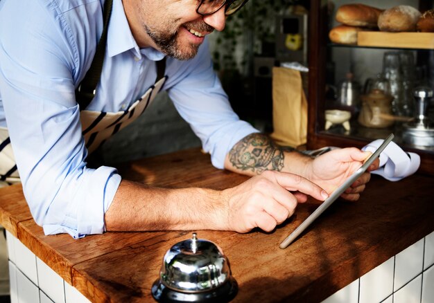Hombre tatuado usando tableta digital en panadería
