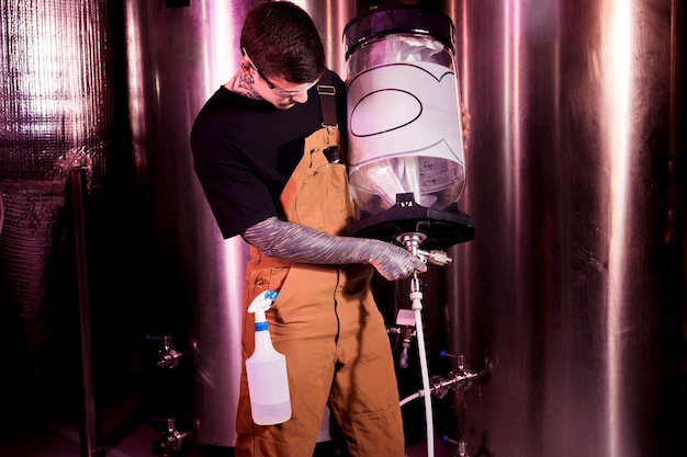 Hombre con tatuajes produciendo cerveza artesana