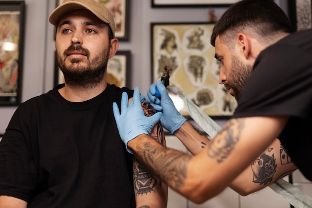 Hombre tatuando con guantes plano medio
