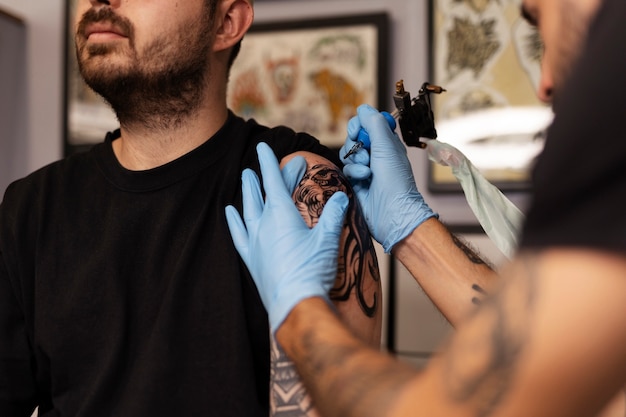 Hombre tatuando con guantes vista lateral