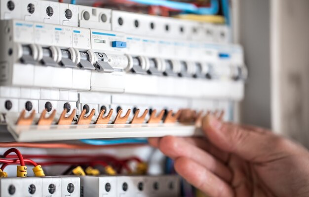 Hombre, un técnico eléctrico que trabaja en una centralita con fusibles. Instalación y conexión de equipos eléctricos. De cerca.