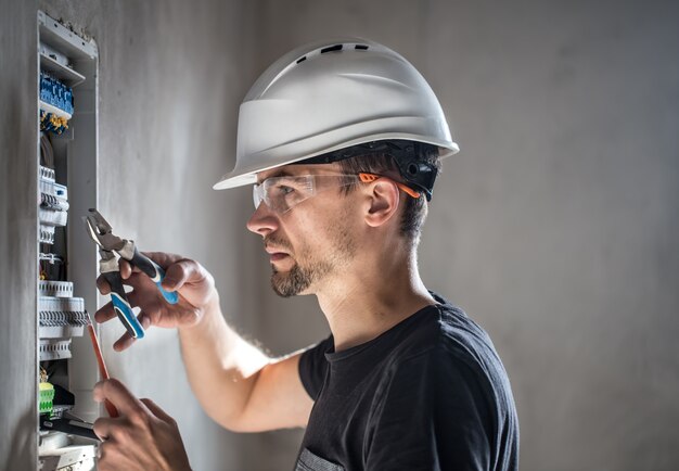 Hombre, un técnico eléctrico que trabaja en una centralita con fusibles. Instalación y conexión de equipos eléctricos.