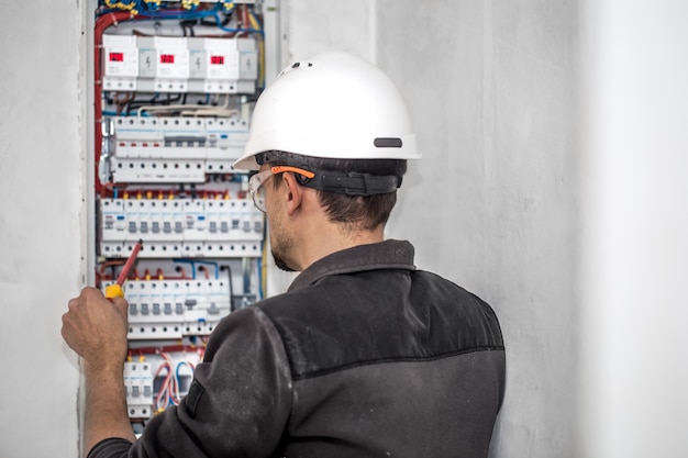 Hombre, un técnico eléctrico que trabaja en una centralita con fusibles. Instalación y conexión de equipos eléctricos.