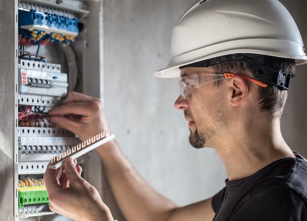 Hombre, un técnico eléctrico que trabaja en una centralita con fusibles. Instalación y conexión de equipos eléctricos.