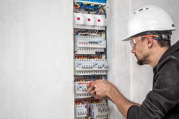 Hombre, un técnico eléctrico que trabaja en una centralita con fusibles. Instalación y conexión de equipos eléctricos.