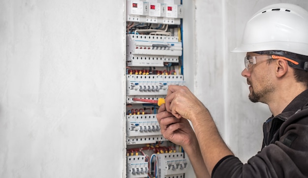 Foto gratuita hombre, un técnico eléctrico que trabaja en una centralita con fusibles