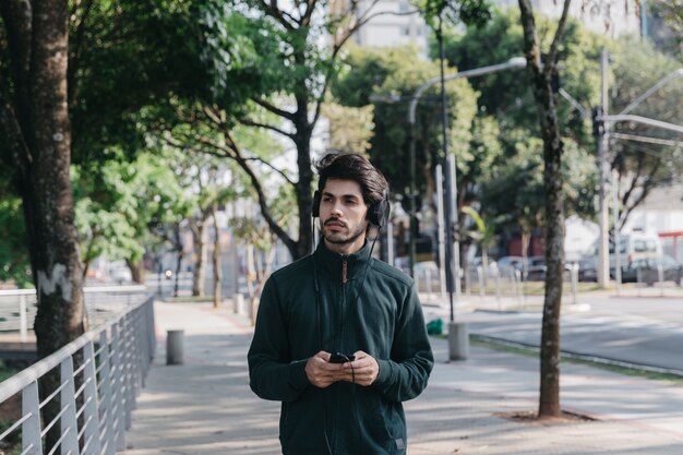 Hombre con teléfono inteligente y auriculares en el parque