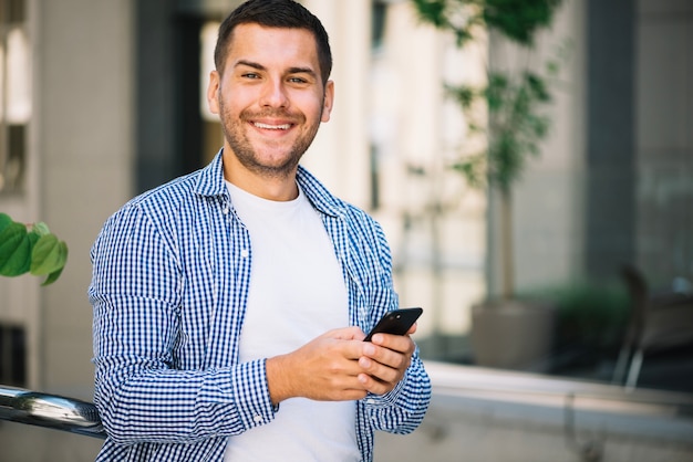 Hombre con teléfono inteligente cerca de la escalera