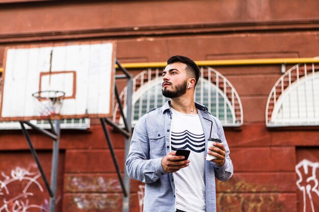 Hombre con teléfono móvil de pie en la cancha de baloncesto