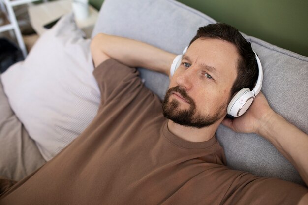 Hombre tendido en la cama escuchando música