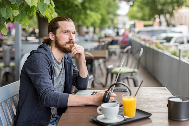 Foto gratuita hombre en una terraza de la ciudad trabajando con laptop