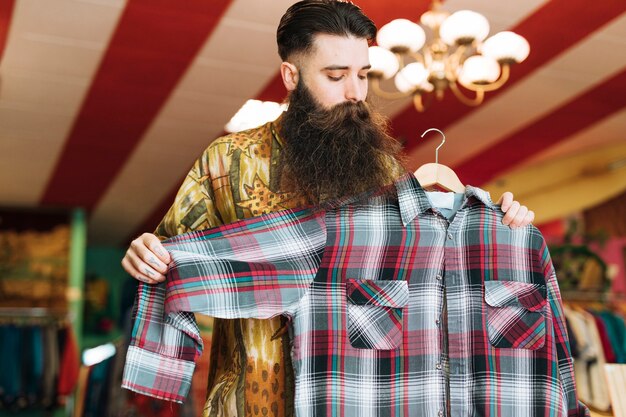 Hombre en una tienda de moda revisando camisa a cuadros