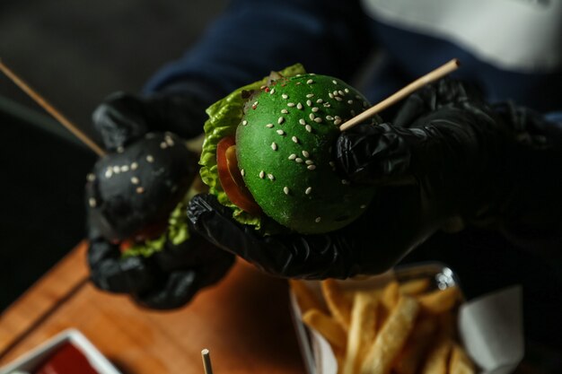 El hombre tiene hamburguesas mixtas en el tablero de madera carne lechuga tomate pepino cebolla vista superior