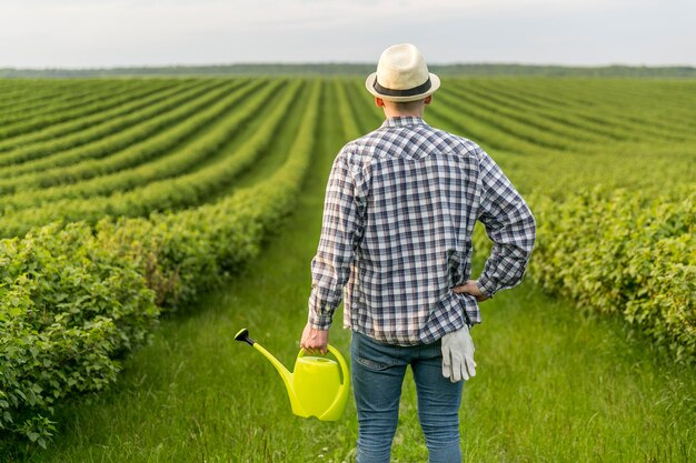 Hombre en tierras de cultivo con regadera