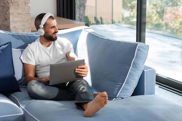 Hombre de tiro completo con auriculares y portátil