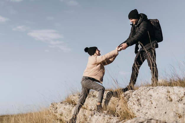 Hombre de tiro completo ayudando a mujer a subir