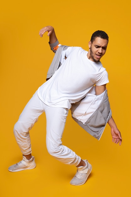 Hombre de tiro completo bailando con fondo amarillo.