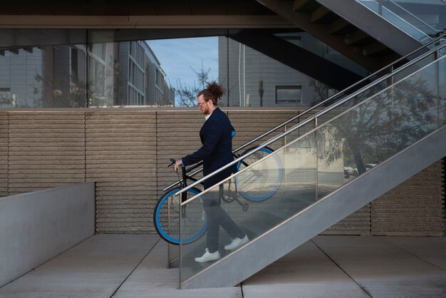 Hombre de tiro completo bajando la bicicleta por las escaleras