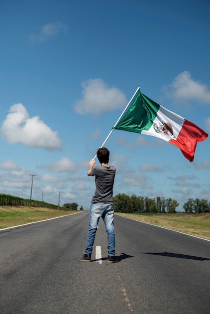 Hombre de tiro completo con bandera mexicana en la calle