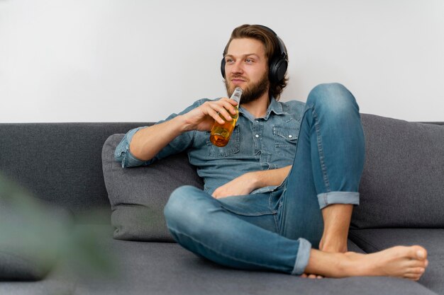 Hombre de tiro completo con bebida y auriculares