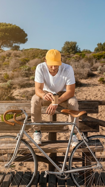 Foto gratuita hombre de tiro completo con bicicleta en un banco