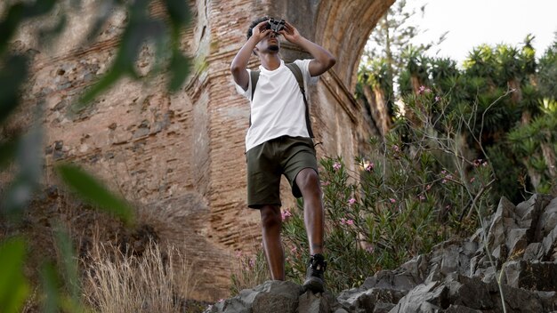 Hombre de tiro completo con binoculares en la naturaleza
