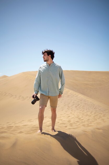Hombre de tiro completo con cámara de fotos en el desierto.