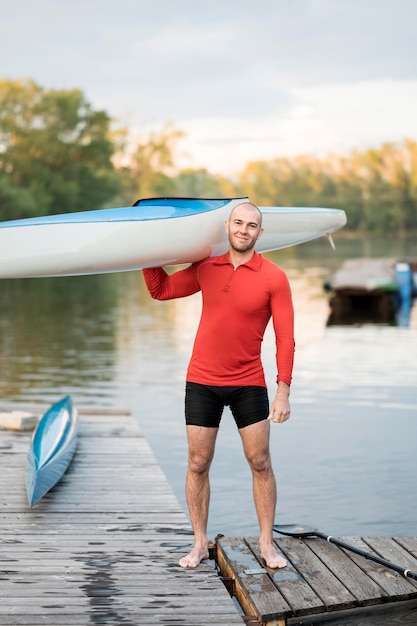 Foto gratuita hombre de tiro completo con canoa en el hombro