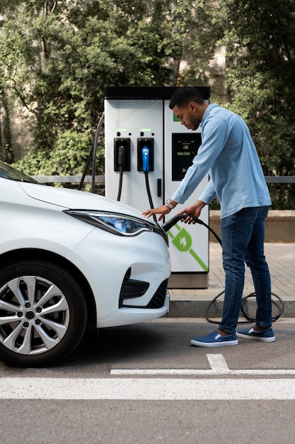 Hombre de tiro completo cargando auto eléctrico