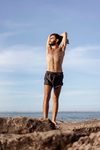 Hombre de tiro completo con cofre peludo en la playa