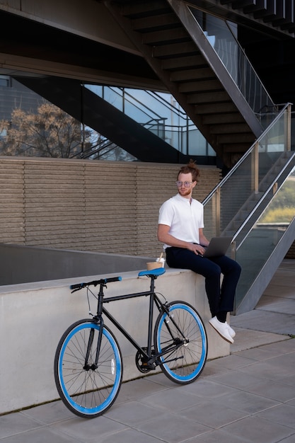 Hombre de tiro completo con computadora portátil y bicicleta