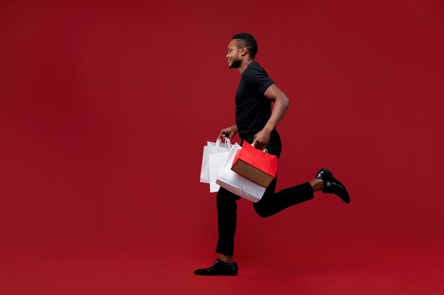 Hombre de tiro completo corriendo con bolsas de la compra.