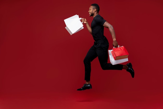 Hombre de tiro completo corriendo con bolsas de la compra.