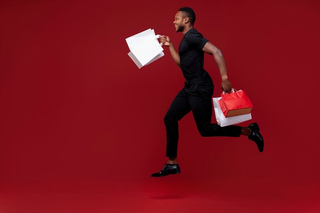 Hombre de tiro completo corriendo con bolsas de la compra.