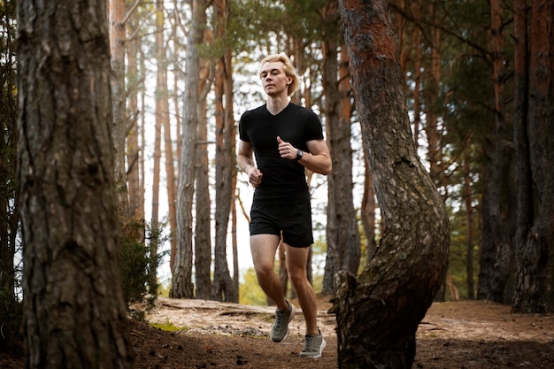 Hombre de tiro completo corriendo en el bosque